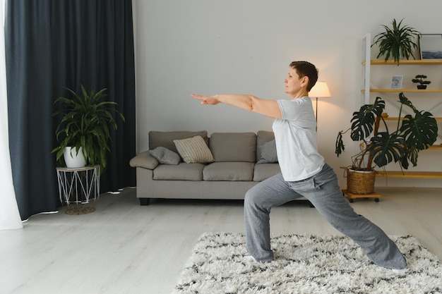 Femme d'âge moyen souriante heureuse de faire de l'exercice et de s'étirer à la maison