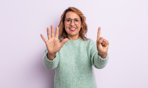 Femme d'âge moyen souriante et semblant amicale, montrant le numéro six ou sixième avec la main vers l'avant, compte à rebours