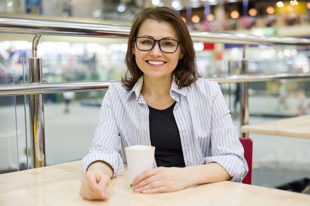 Femme d'âge moyen à une table avec une tasse de café