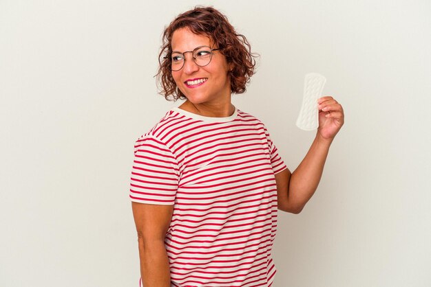 Une femme d'âge moyen tenant une compresse isolée sur fond blanc regarde de côté souriante, gaie et agréable.