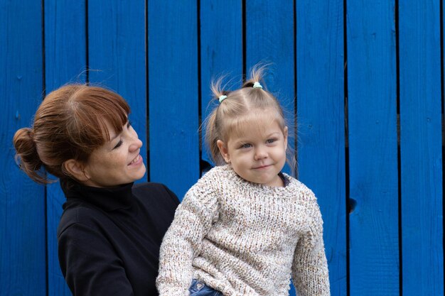 Femme d'âge moyen tenant un enfant sur les mains sur un fond en bois bleu