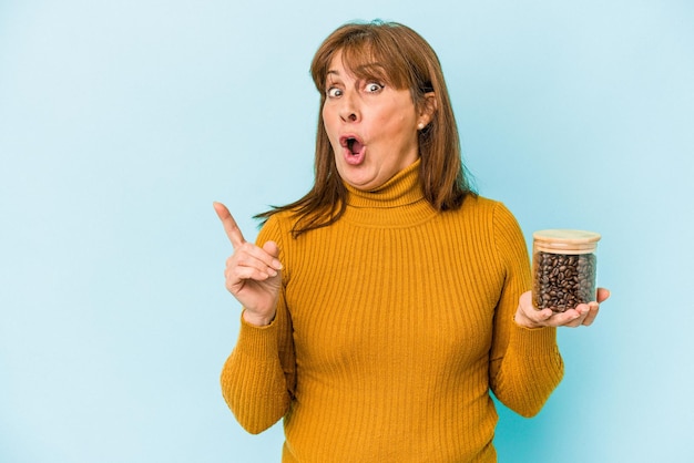 Femme d'âge moyen tenant un pot de café isolé sur fond bleu