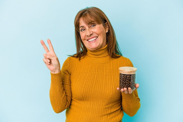 Femme d'âge moyen tenant un pot de café isolé sur fond bleu