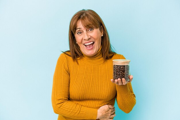 Femme d'âge moyen tenant un pot de café isolé sur fond bleu