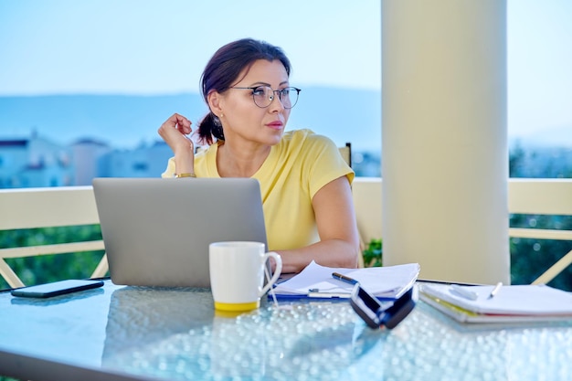 Femme d'âge moyen travaillant dans un bureau à domicile sur une terrasse