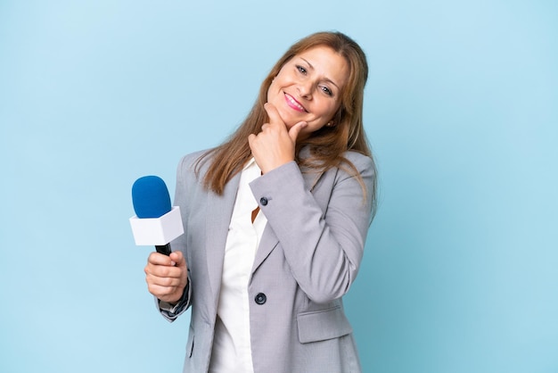 Femme d'âge mûr présentatrice de télévision sur fond bleu isolé heureux et souriant