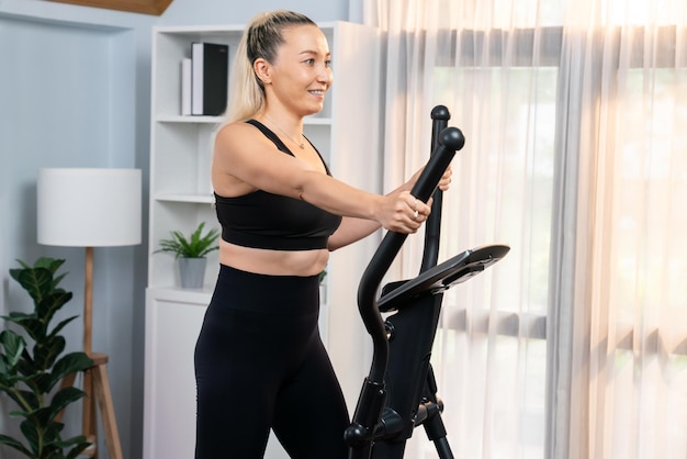 Femme âgée active courant sur une machine elliptique à la maison, portrait comme mode de vie sain et soins du corps après la retraite pour le retraité Clout