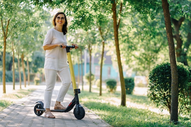 Une femme âgée adorable et joyeuse qui utilise un scooter alors qu'elle roule dans le parc