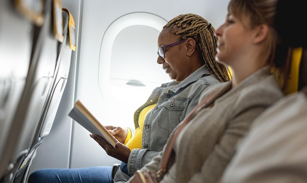 Femme âgée africaine lisant un livre en volant en avion Concept de voyage et de vol Se concentrer sur le visage