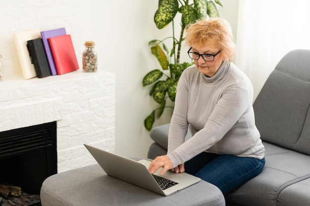 Femme âgée âgée souriante avec ordinateur portable à la maison.