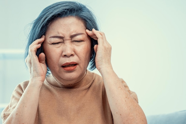 Une femme âgée agonisante avec un mal de tête dans son environnement satisfait