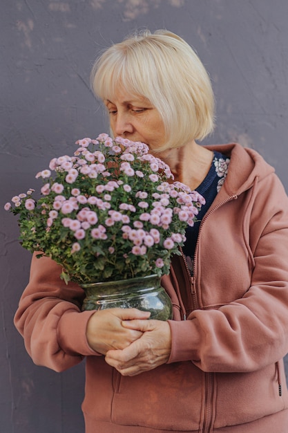 femme âgée aime le parfum des fleurs. Femme âgée exerçant son pot avec des fleurs fraîches