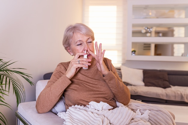 Une femme âgée a des allergies et elle utilise un vaporisateur nasal pour s'aider.