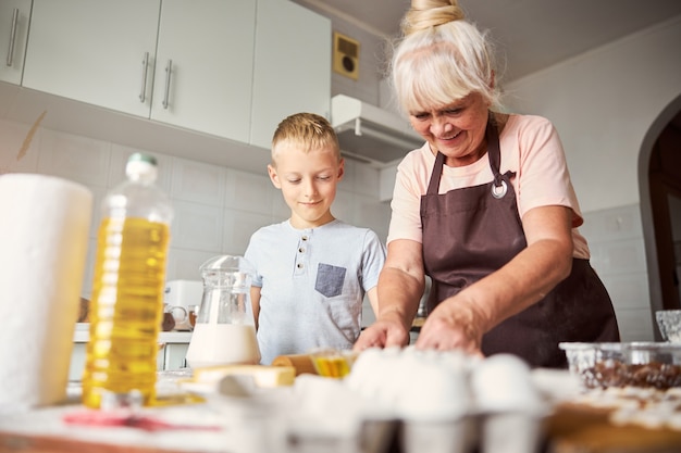 Femme âgée amicale cuisinant avec son petit-fils