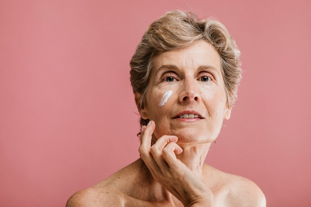 Femme âgée appliquant une crème pour le visage