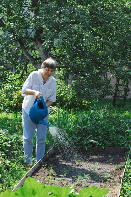 Une femme âgée arrosant les plantes dans le jardin