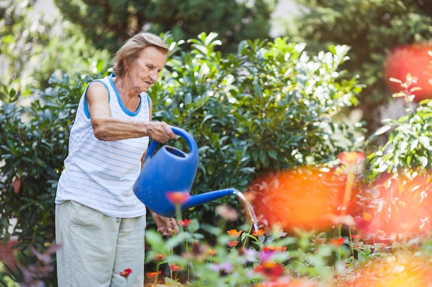 Photo femme âgée arrosant les plantes de son jardin