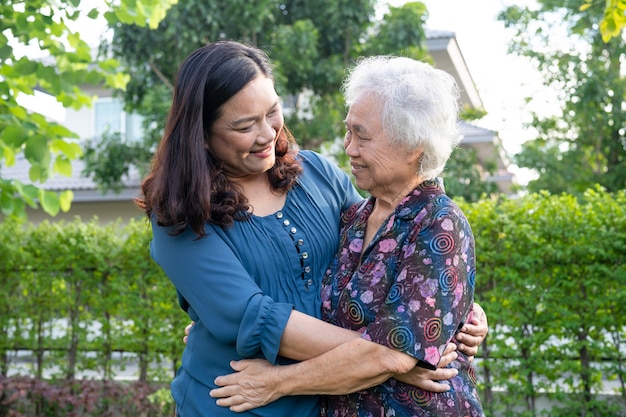 Femme âgée asiatique avec aide soignante marchant avec amour et heureuse dans le parc naturel.