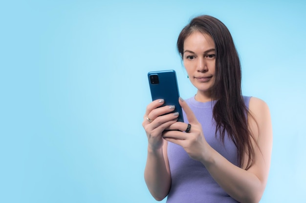 Femme âgée asiatique à l'aide d'un téléphone intelligent avec un fond bleu