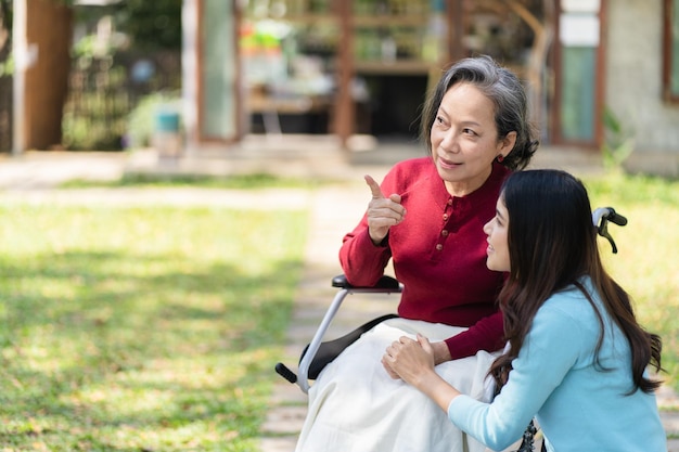 Une femme âgée asiatique en fauteuil roulant avec une fille heureuse Relation familiale Une femme à la retraite assise