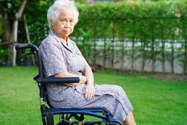 Femme âgée asiatique handicapée patiente assise sur un fauteuil roulant dans le concept médical du parc
