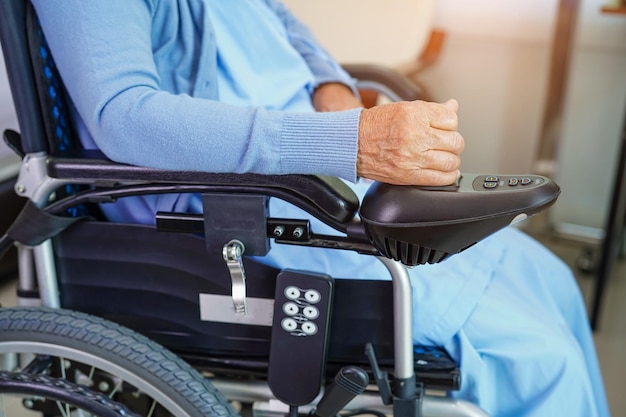 Femme âgée asiatique handicapée patiente assise sur un fauteuil roulant électrique dans le concept médical du parc