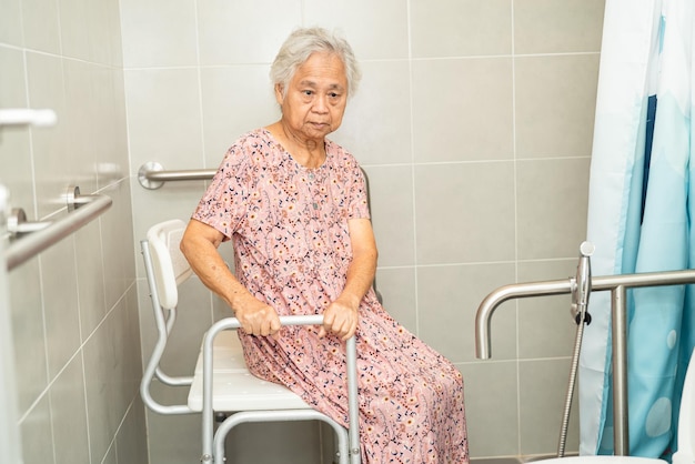 Femme âgée asiatique patient utiliser la sécurité de la poignée de salle de bain des toilettes dans l'hôpital de soins infirmiers sain concept médical fort