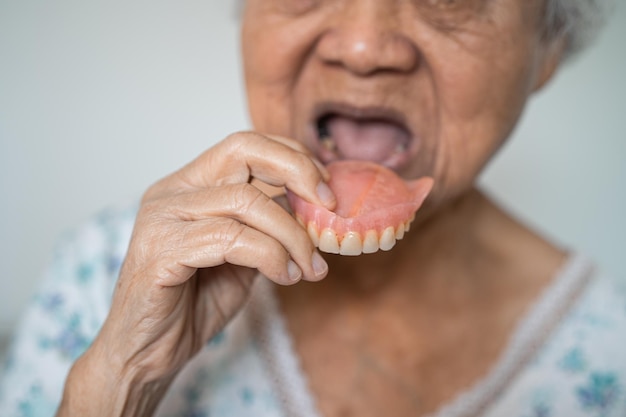 Femme âgée asiatique patiente tenant pour utiliser une prothèse saine concept médical fort