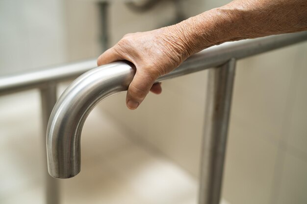 Une femme âgée asiatique patiente utilise la sécurité de la poignée de la salle de bain des toilettes dans l'hôpital de soins infirmiers concept médical fort et sain