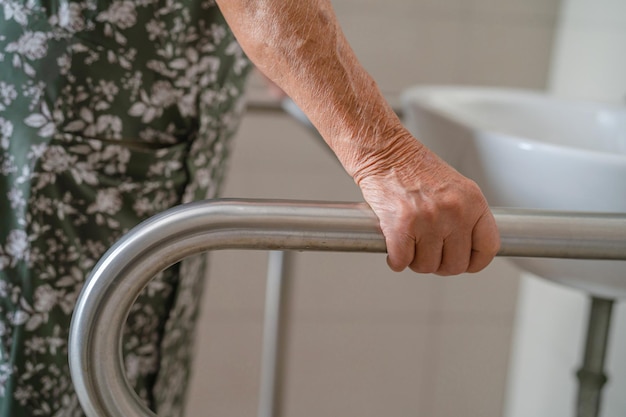 Une femme âgée asiatique patiente utilise la sécurité de la poignée de la salle de bain des toilettes dans l'hôpital de soins infirmiers concept médical fort et sain