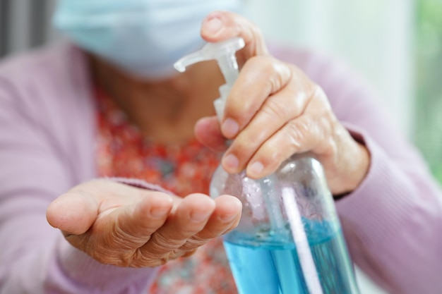 Une femme âgée asiatique presse un gel désinfectant à l'alcool bleu pour se laver les mains protège l'infection coronavirusxAAUne femme âgée asiatique presse un gel désinfectant à l'alcool bleu pour se laver les mains protège l'infection coronavirus