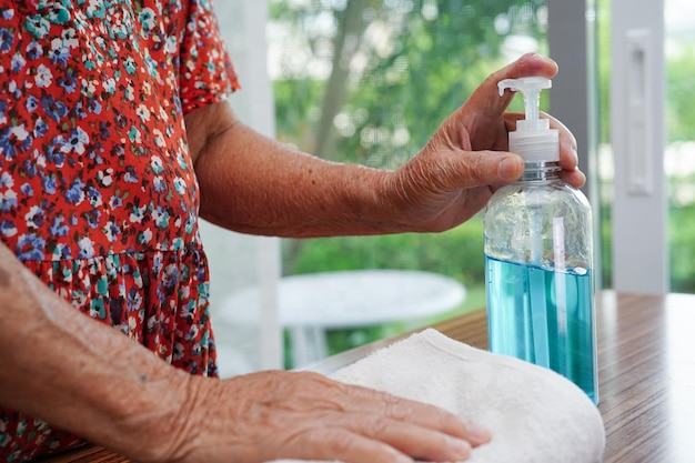 Une femme âgée asiatique presse un gel désinfectant à l'alcool bleu pour se laver les mains protéger le coronavirus de l'infection