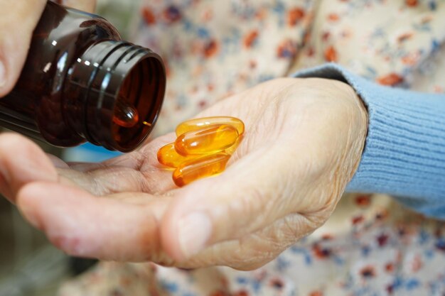 Femme âgée asiatique tenant un médicament en pilule dans la main concept médical sain et fort