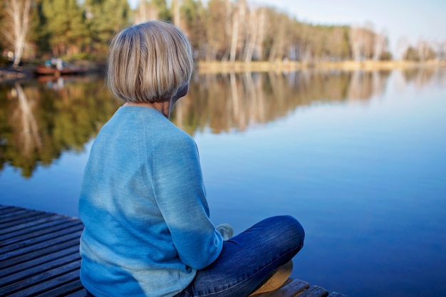 Photo une femme âgée assise au bord du lac se repose et profite d'une santé mentale calme et naturelle