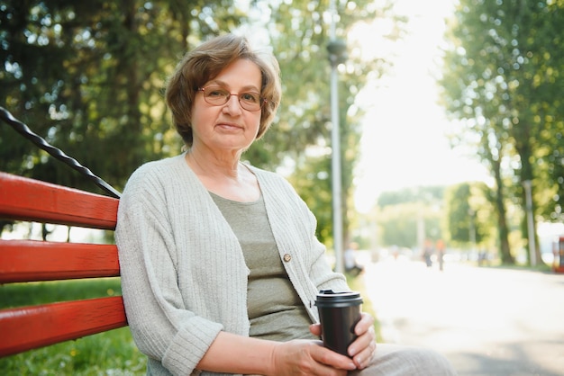 Une femme âgée assise sur un banc dans le parc d'été