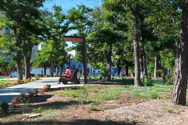 Femme âgée assise sur un banc de parc un soir d'été dans la ville