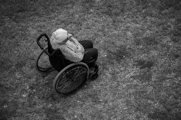 Femme âgée assise dans un fauteuil roulant sur fond d'herbe