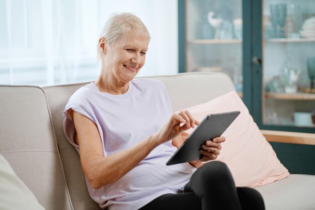 Femme âgée assise dans une pose de yoga devant un ordinateur portable ouvert