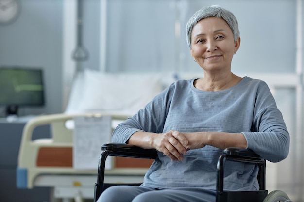 Femme âgée assise en fauteuil roulant dans la salle