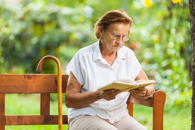 Femme âgée assise et relaxante sur un banc dans le parc