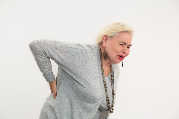 Femme âgée ayant des maux de dos dame isolée touchant son dos comment guérir le lumbago