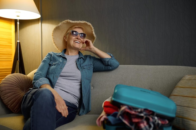 Femme âgée avec bagages emballés pour le voyage