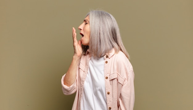 Femme âgée bâillant paresseusement tôt le matin, se réveillant et ayant l'air endormi, fatigué et ennuyé