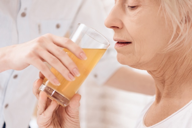 Femme âgée buvant du jus à l'hôpital.