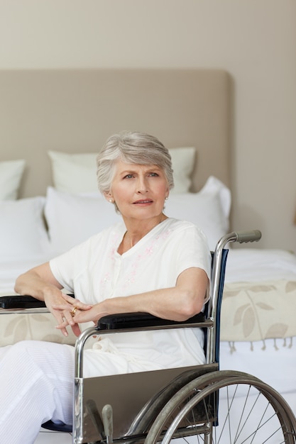 Femme âgée concentrée dans son fauteuil roulant à la maison