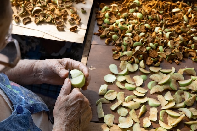 Une femme âgée coupe une pomme en morceaux et les met à sécher