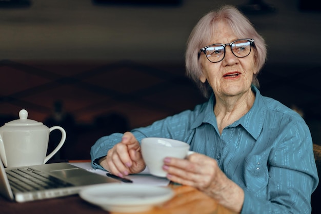 Femme âgée dans un café une tasse de boisson portable Réseaux sociaux inchangés