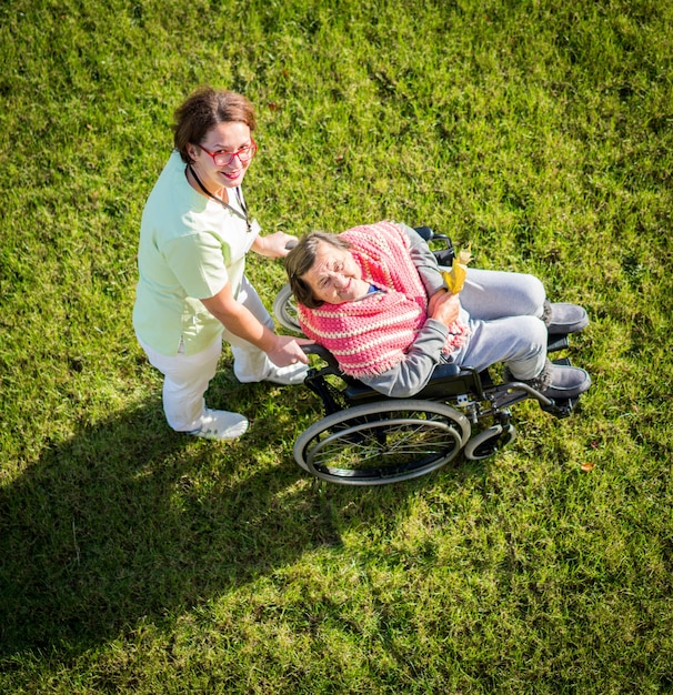Femme âgée, dans, fauteuil roulant, vue haut, sur, herbe, à, infirmière, prendre soin, de, elle