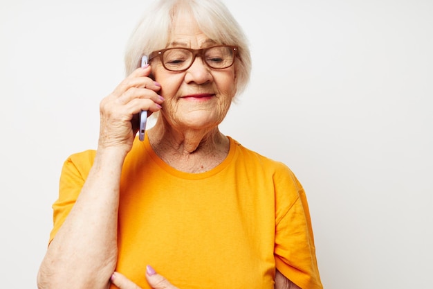 Femme âgée dans des lunettes de t-shirt décontracté parlant au téléphone émotions en gros plan