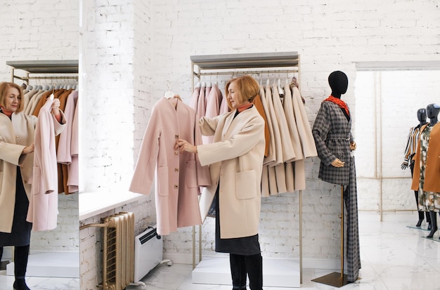 Une femme âgée dans un magasin de vêtements choisit un manteau Shopping acheter des vêtements